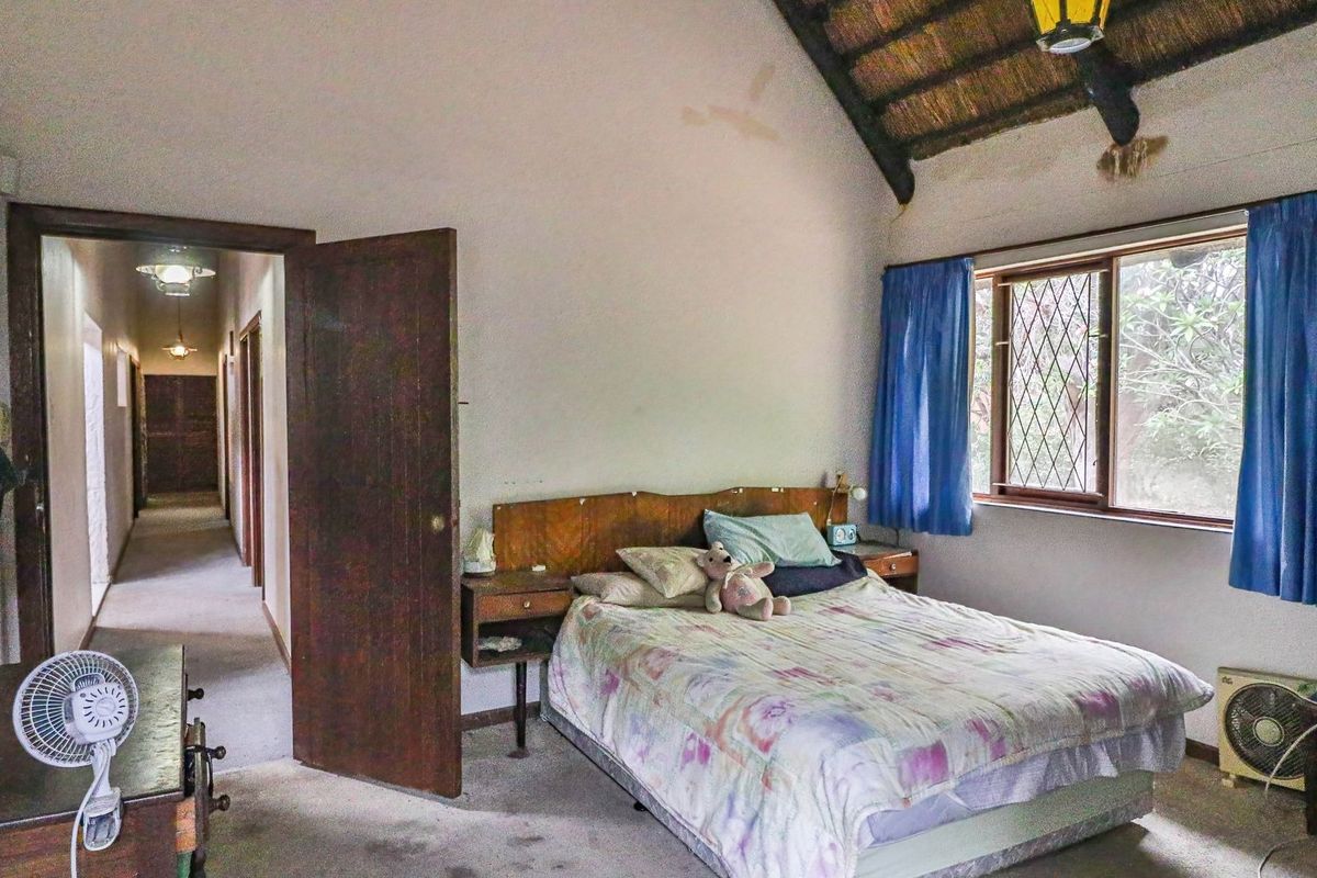 Bedroom featuring an exposed thatch ceiling, leaded glass windows, and built-in headboard, requiring cosmetic updates to the flooring and ceiling finishes.