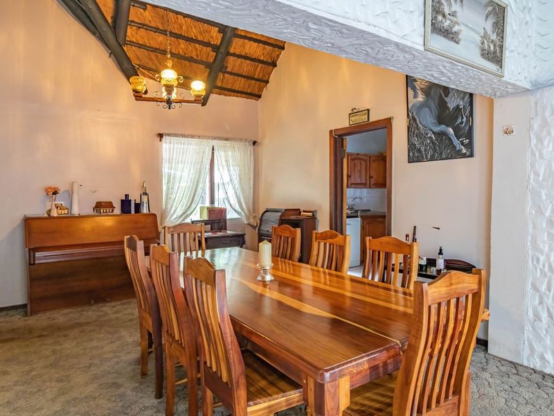 Dining room featuring a high exposed thatch ceiling, textured wall finishes, and direct access to the kitchen area.