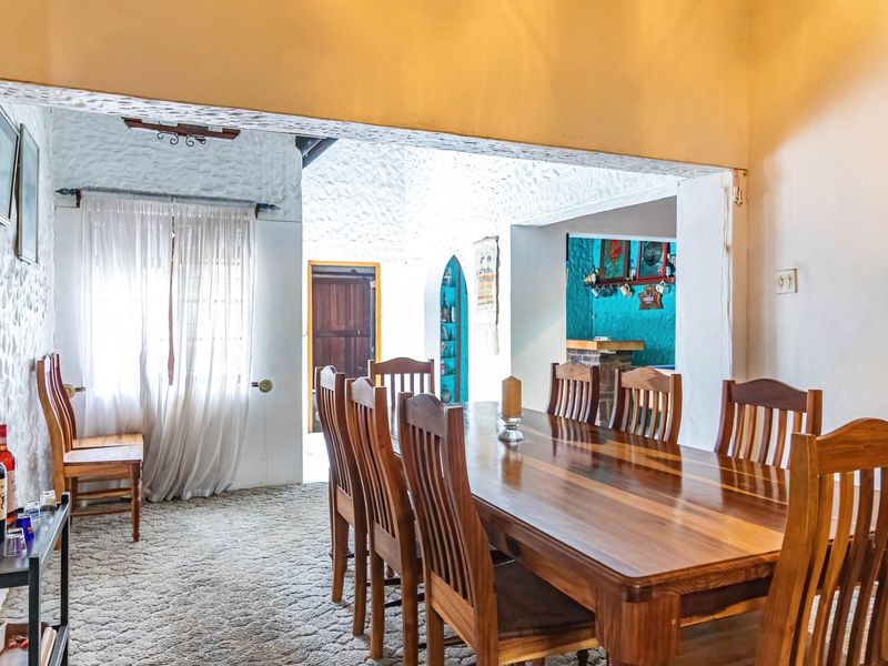 Dining room featuring textured walls, an open archway leading to adjacent living spaces, and built-in shelving details.