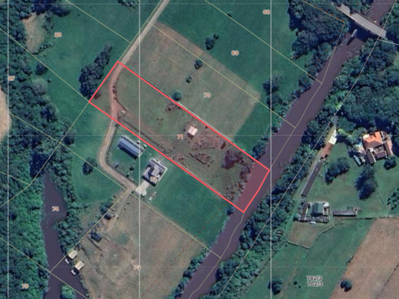 Aerial view of a vacant residential plot featuring river frontage and clearly marked property boundaries.