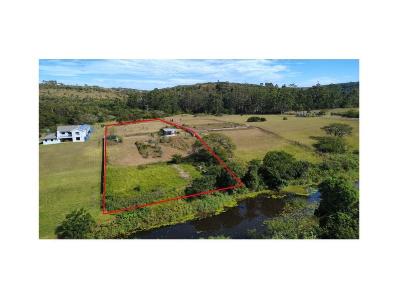 Aerial view of a residential vacant land plot featuring defined boundaries, natural vegetation, and proximity to a water feature.