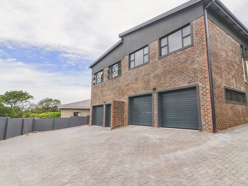 Modern double-story townhouse featuring a face-brick facade, three secure garage bays, and a spacious paved driveway area.