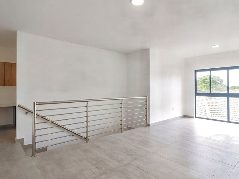 A bright and spacious landing area featuring modern tiled flooring, a sleek stainless steel balustrade, and large windows providing ample natural light.