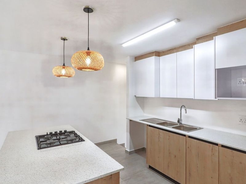 Modern kitchen featuring a central island with a gas hob, stone countertops, double sink, and contemporary wood-finish cabinetry.