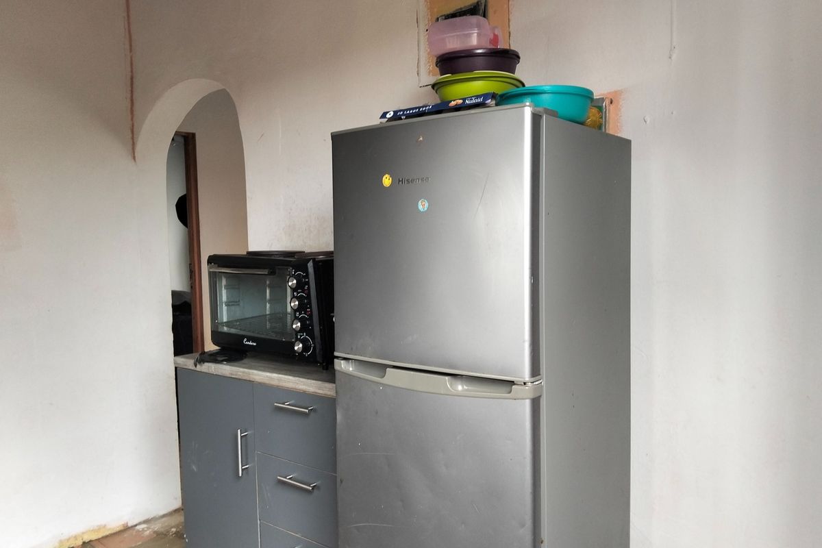 A small kitchen area featuring built-in grey cabinetry and a countertop, currently requiring wall finishing and repairs to the surrounding plaster and electrical points.