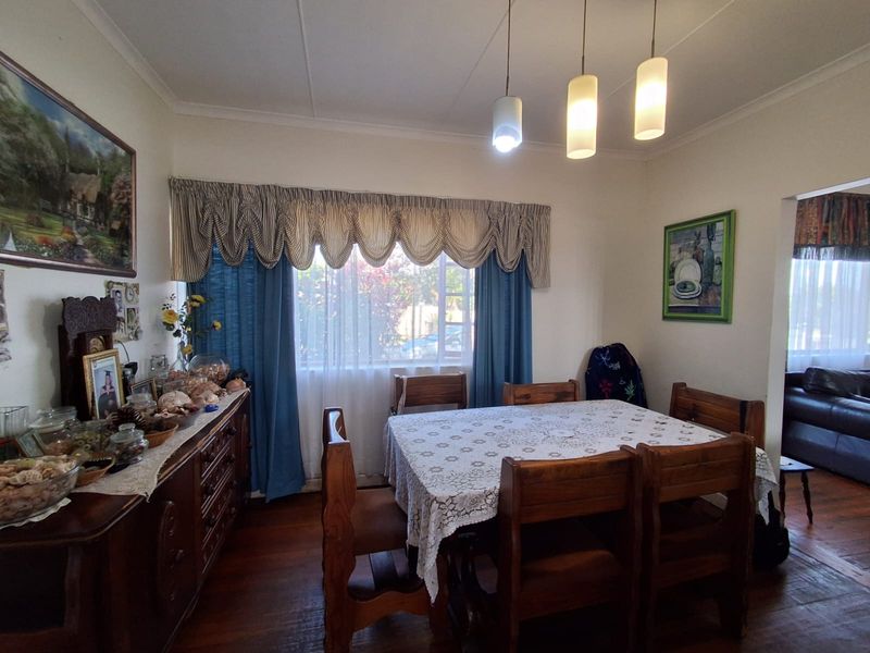 A dining room featuring hardwood flooring, coved ceilings, and pendant lighting, offering a traditional layout with access to an adjacent living area.