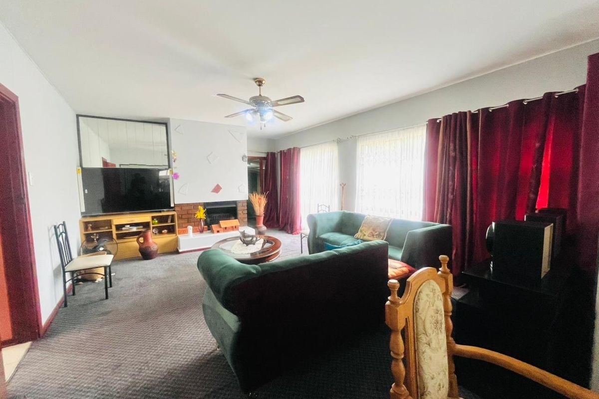 A spacious living room featuring a brick fireplace, ceiling fan, and large wall mirror, offering a comfortable area for relaxation.