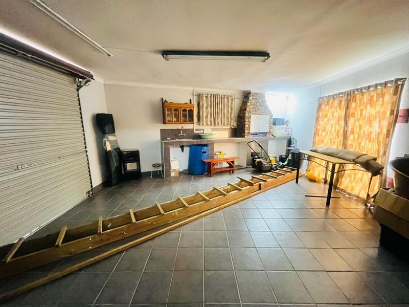 Spacious garage featuring tiled flooring, a built-in sink, and a brick fireplace, offering versatile utility space with direct access.
