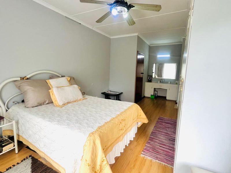 A bedroom featuring laminate flooring, a ceiling fan, and a built-in vanity area with integrated storage.