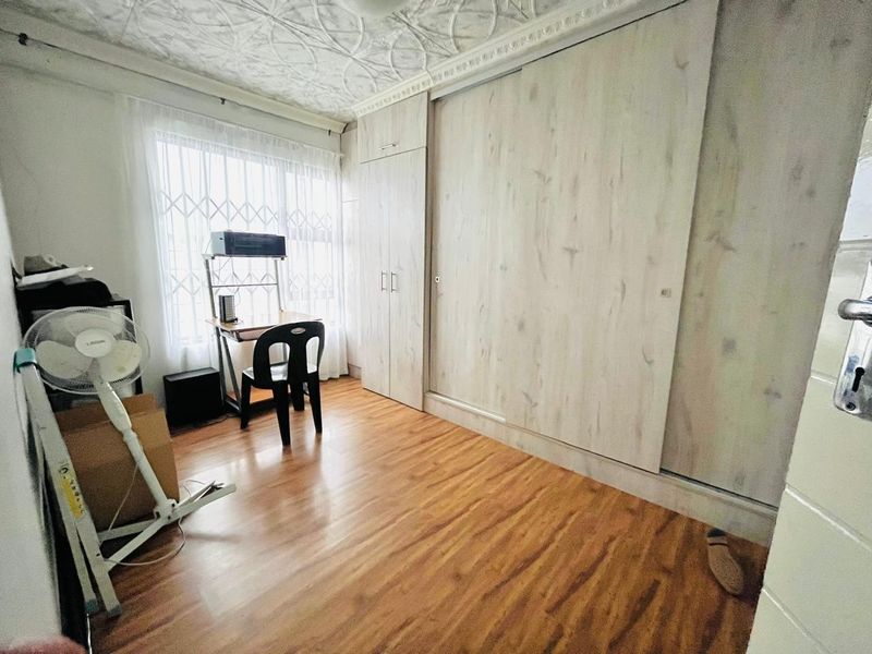 Bedroom featuring laminate flooring, decorative ceiling details, and extensive built-in cupboard storage space.