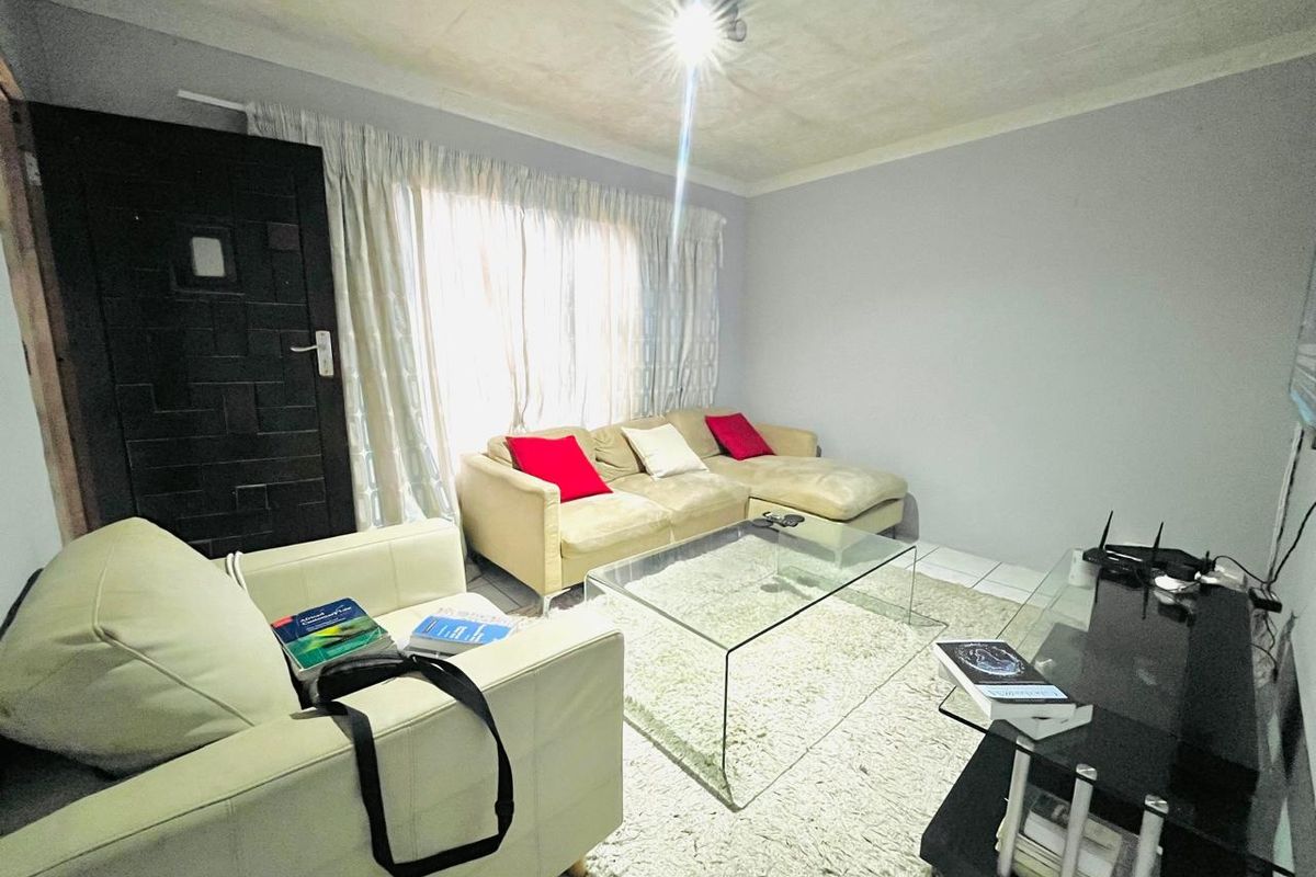 A living room featuring tiled flooring and a coved ceiling, requiring cosmetic updates to address ceiling condition.