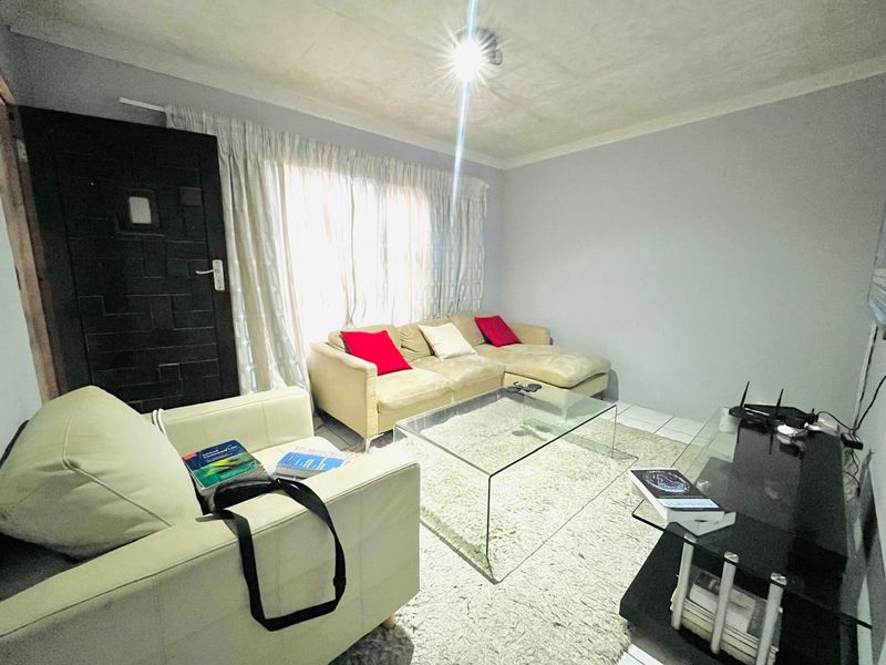 A living room featuring tiled flooring and a coved ceiling, requiring cosmetic updates to address ceiling condition.