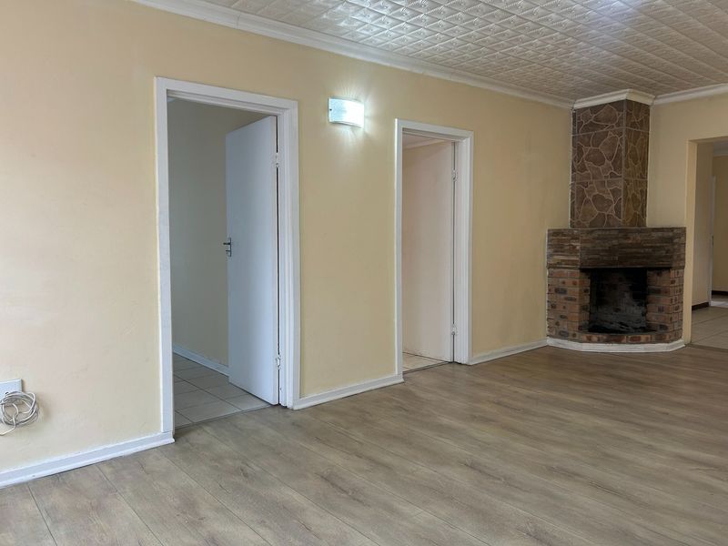 Spacious living area featuring a stone fireplace, laminate flooring, and textured ceiling tiles, offering a blank canvas for personalization.