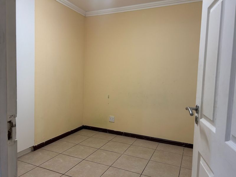 An empty bedroom featuring tiled flooring and neutral wall paint, ready for personalization or staging.
