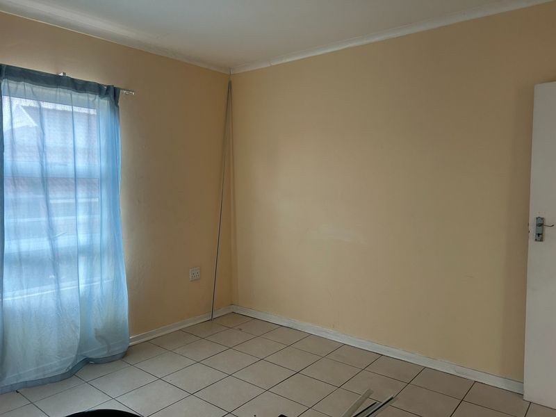 An empty bedroom featuring tiled flooring and neutral wall paint, providing a blank canvas for potential interior design updates.
