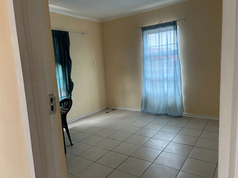 An empty bedroom featuring neutral tiled flooring and dual windows with existing curtain rods, offering a blank canvas for personalization.