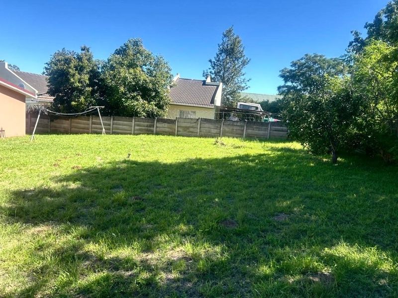 A spacious backyard garden featuring a well-maintained lawn enclosed by a precast concrete boundary wall with security razor wire.