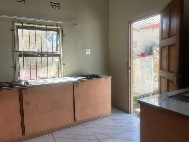 A functional kitchen space featuring built-in cabinetry, a hob, and tiled flooring, with direct access to an outdoor area.