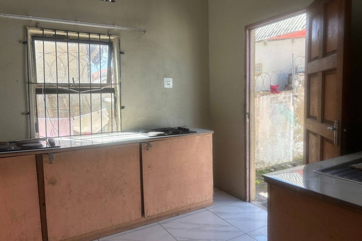 A functional kitchen space featuring built-in cabinetry, a hob, and tiled flooring, with direct access to an outdoor area.