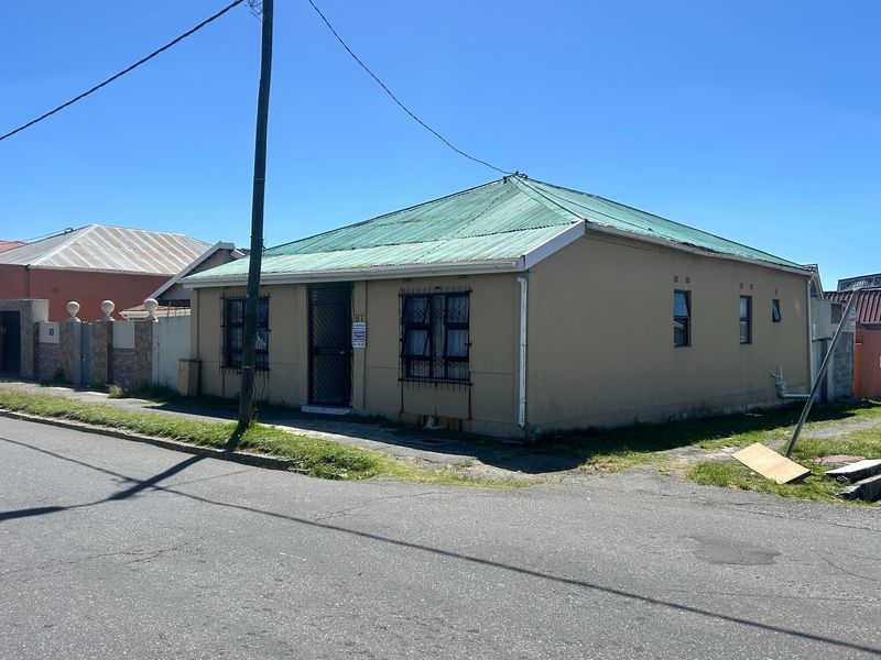 Front elevation of a single-story detached house featuring a corrugated metal roof, security bars on windows, and a security gate entrance.