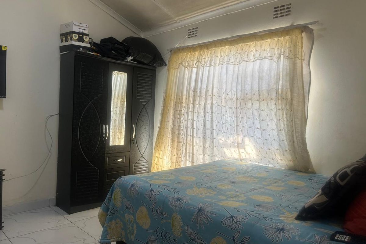 A bedroom featuring tiled flooring and a vaulted ceiling with integrated ventilation grilles.