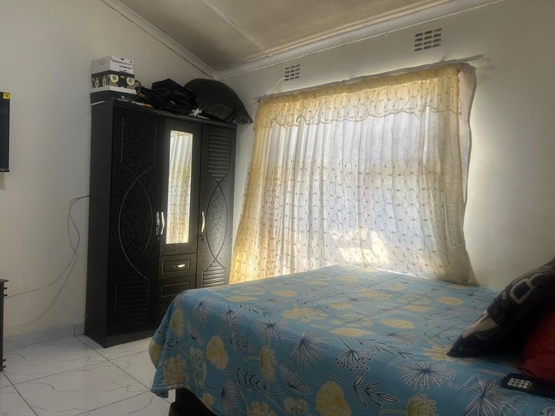 A bedroom featuring tiled flooring and a vaulted ceiling with integrated ventilation grilles.