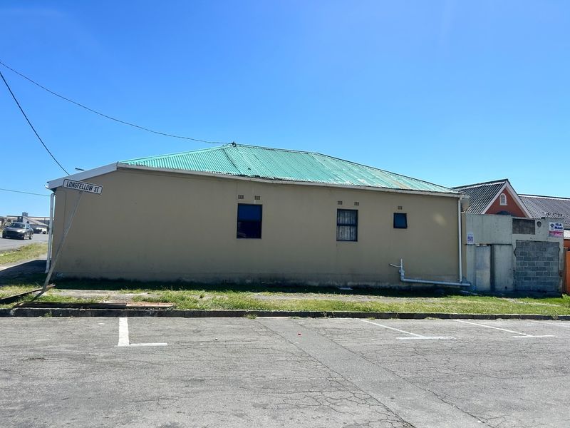 Street-facing exterior view of a single-story house with a green corrugated metal roof and security-barred windows.
