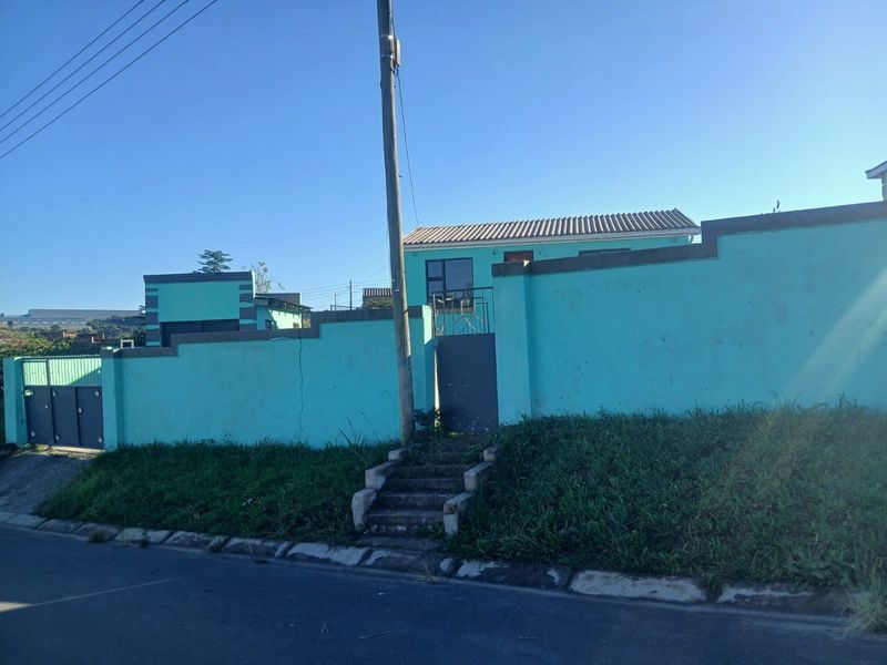 Front exterior view of the property featuring a boundary wall, pedestrian gate, vehicle access gate, and concrete steps leading to the entrance.