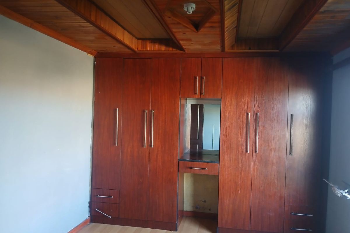 Bedroom featuring extensive built-in wooden cabinetry with an integrated vanity unit and a distinctive timber-paneled ceiling.