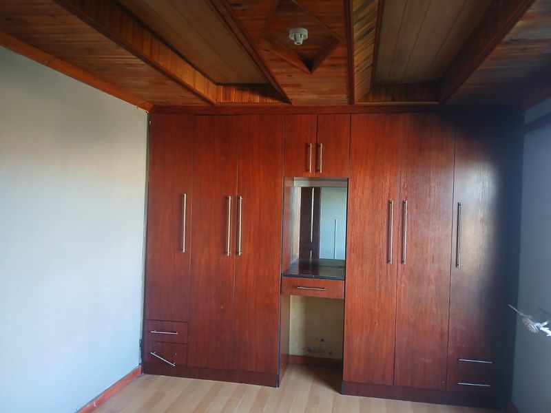 Bedroom featuring extensive built-in wooden cabinetry with an integrated vanity unit and a distinctive timber-paneled ceiling.
