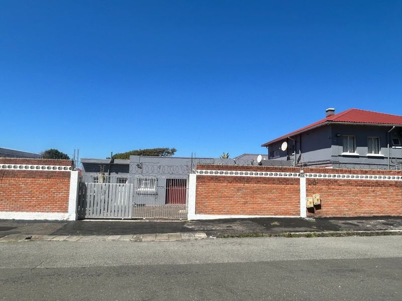 Front exterior view of the property featuring a brick boundary wall with security razor wire and metal access gates.
