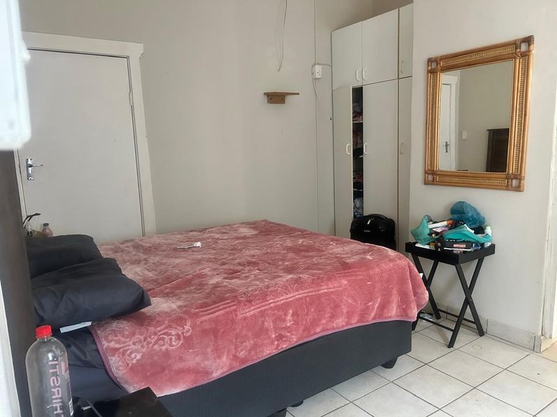 A bedroom featuring built-in wardrobes and tiled flooring, requiring minor cosmetic updates and repairs to wall finishes.