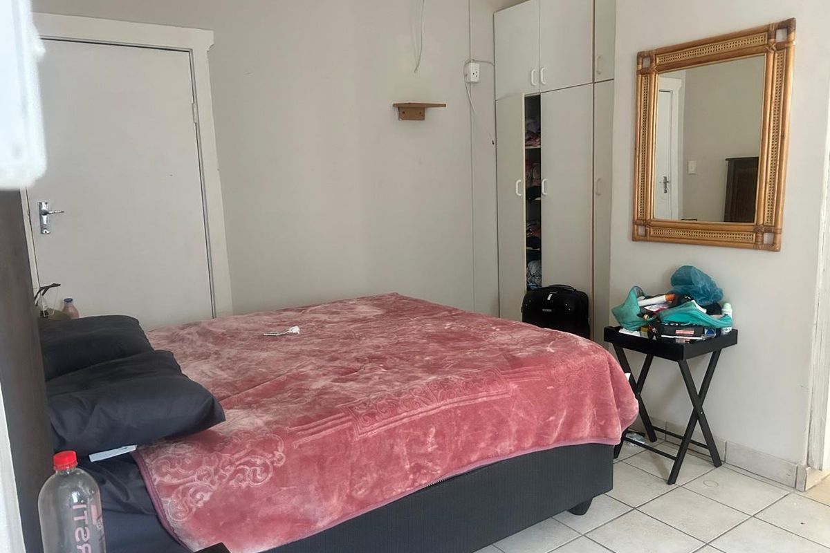 A bedroom featuring built-in wardrobes and tiled flooring, requiring minor cosmetic updates and repairs to wall finishes.