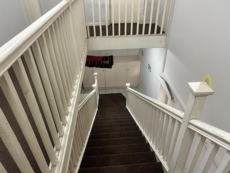 A functional staircase and hallway area featuring a traditional wooden balustrade and built-in storage cabinetry at the landing.