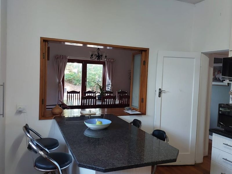 Kitchen featuring a granite breakfast bar and a convenient pass-through window looking into the dining area.