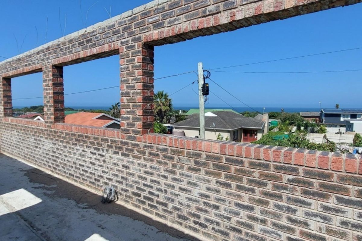 An unfinished elevated balcony or terrace featuring exposed brickwork and expansive coastal views, currently in a shell construction state.