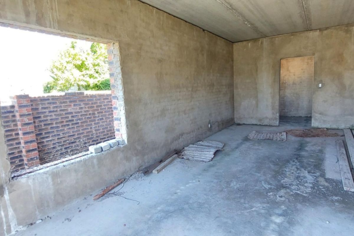 An unfinished interior space in shell condition, featuring raw plastered walls, concrete flooring, and a large window opening, ready for final finishes.