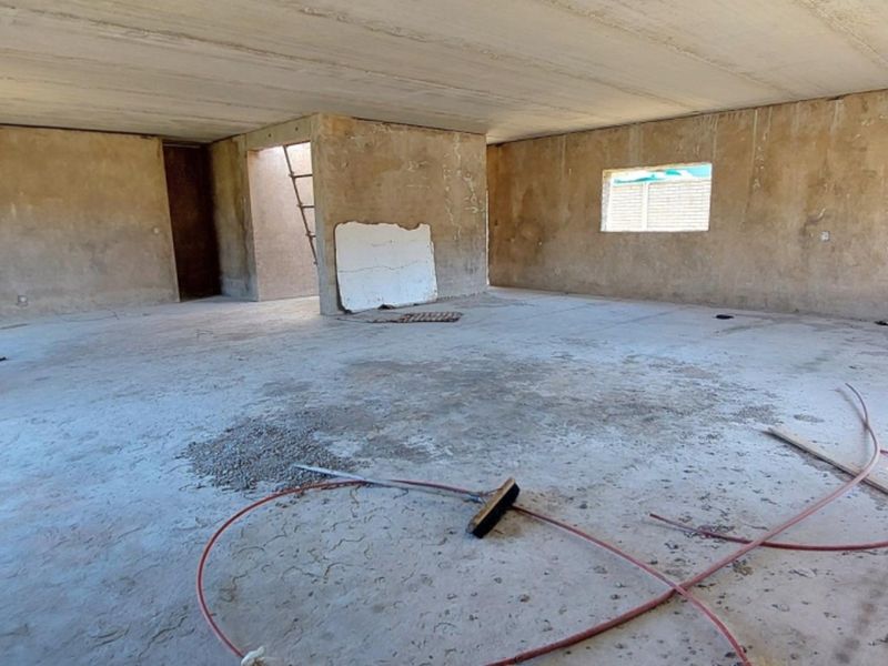 An expansive, unfinished open-plan living area featuring raw concrete flooring, plastered walls, and an exposed concrete ceiling, ready for custom interior finishes.