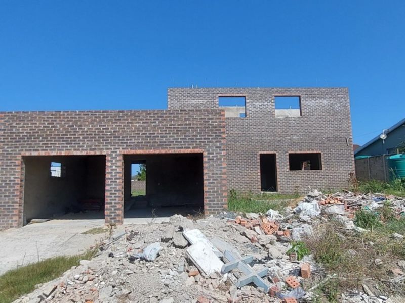 Front view of a double-story face brick house under construction, featuring a double garage and unfinished exterior grounds.