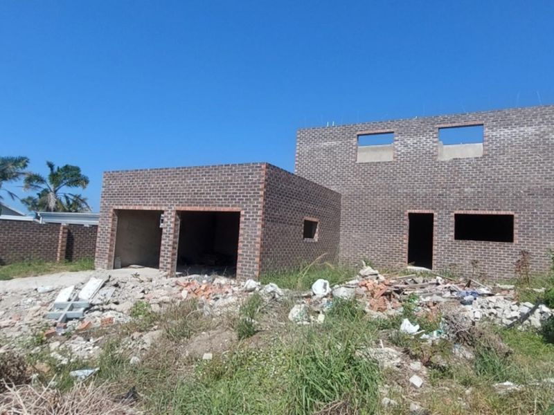 An unfinished brick residential property under construction, featuring a double garage and exterior site debris.