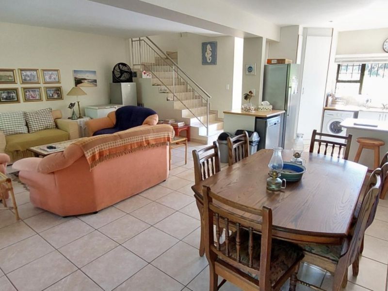 Spacious open-plan living, dining, and kitchen area featuring tiled flooring, a central staircase, and functional kitchen cabinetry.