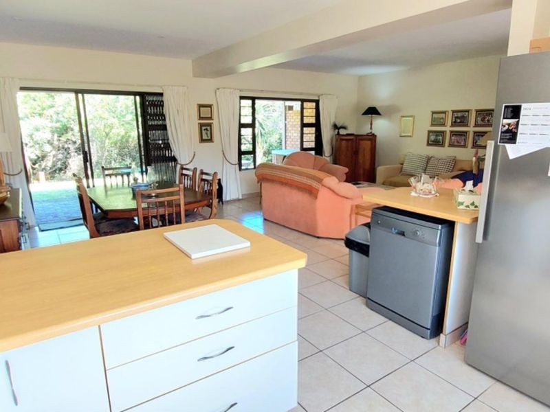Open-plan kitchen and living area featuring tiled flooring, functional cabinetry, and sliding glass doors providing access to the outdoor space.