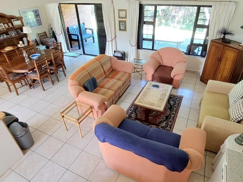 Spacious open-plan living and dining area featuring tiled flooring, large windows, and direct access to the outdoor patio through sliding glass doors.