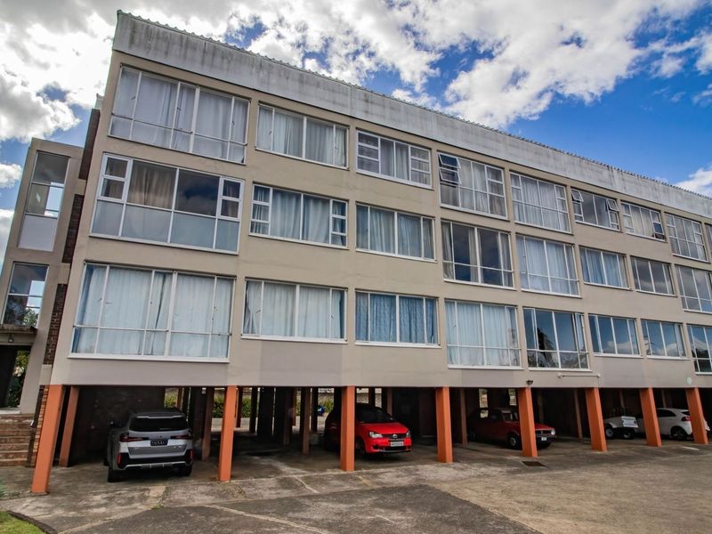 Exterior view of a multi-story apartment building featuring a stilted ground level for undercover parking and large windows across the residential floors.