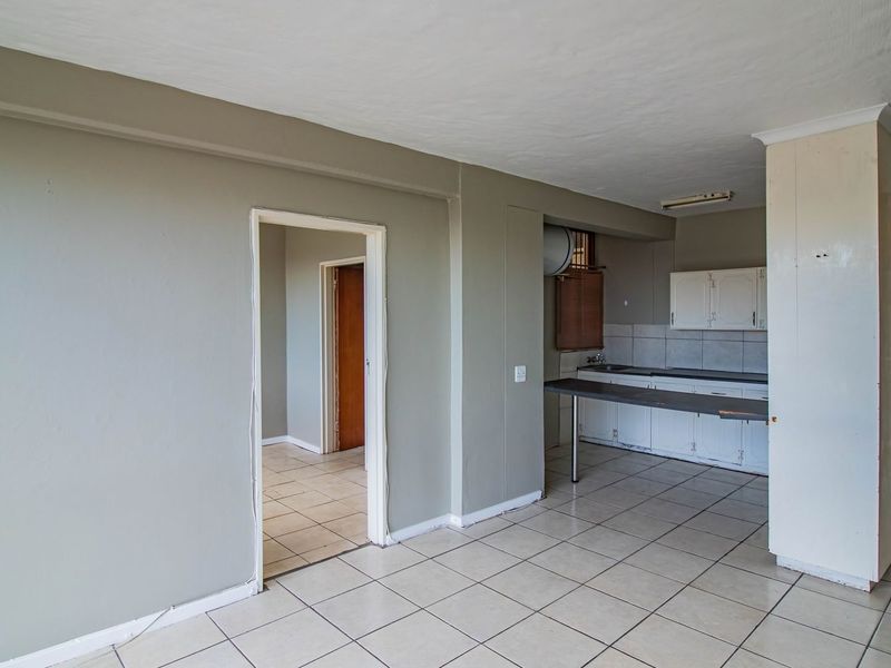 Open plan living area featuring tiled flooring and a functional kitchen with built-in cabinetry and a breakfast counter.