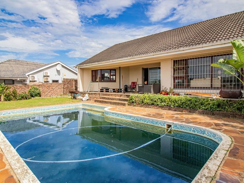Rear garden featuring a swimming pool with paved surround, brick boundary wall, and direct access to the main house structure.