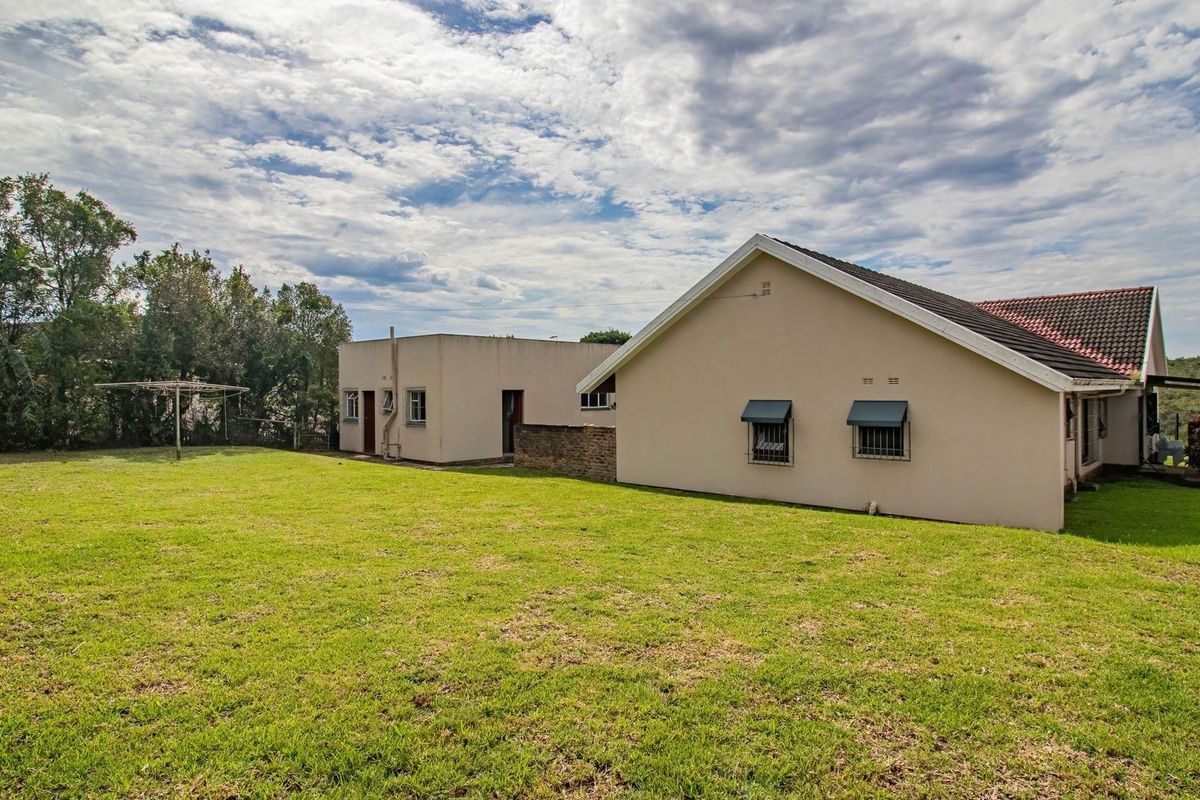 A view of the rear exterior of the house, featuring a large lawn area, tiled roof, and security-fitted windows.