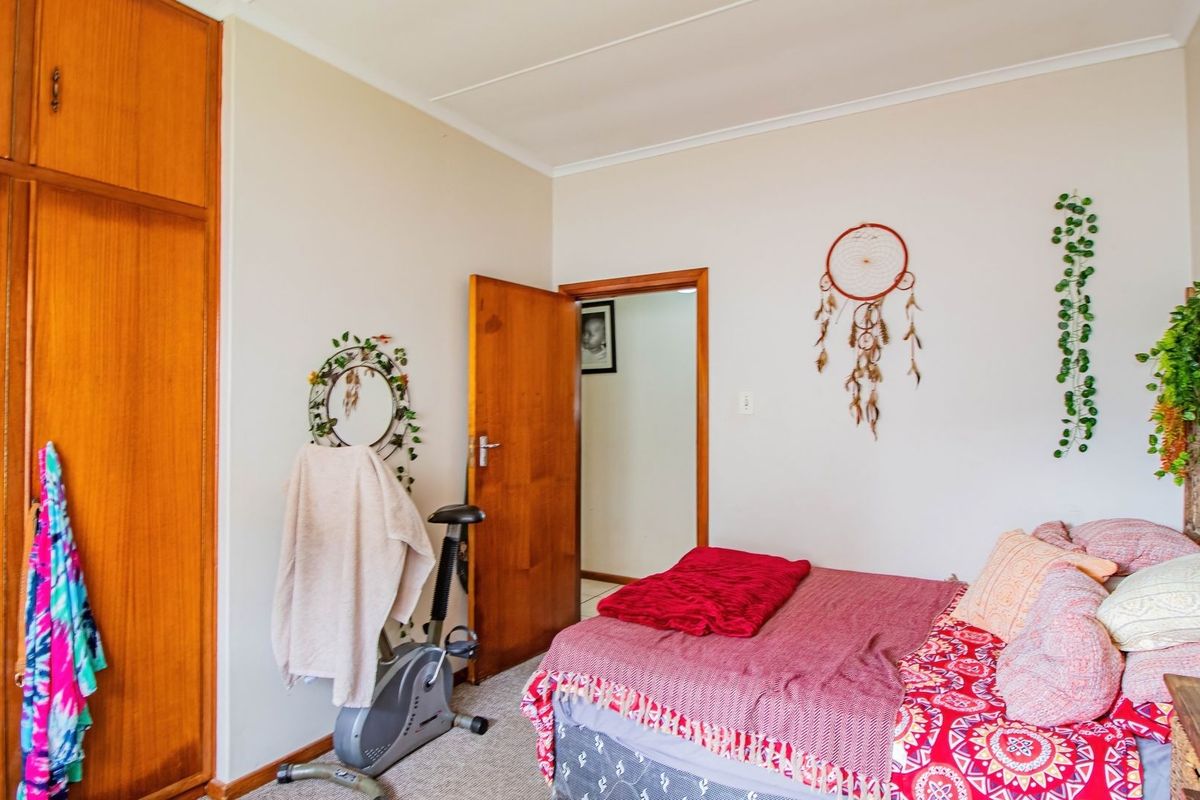 A bedroom featuring a built-in wooden wardrobe, carpeted flooring, and a standard wooden door leading to the hallway.