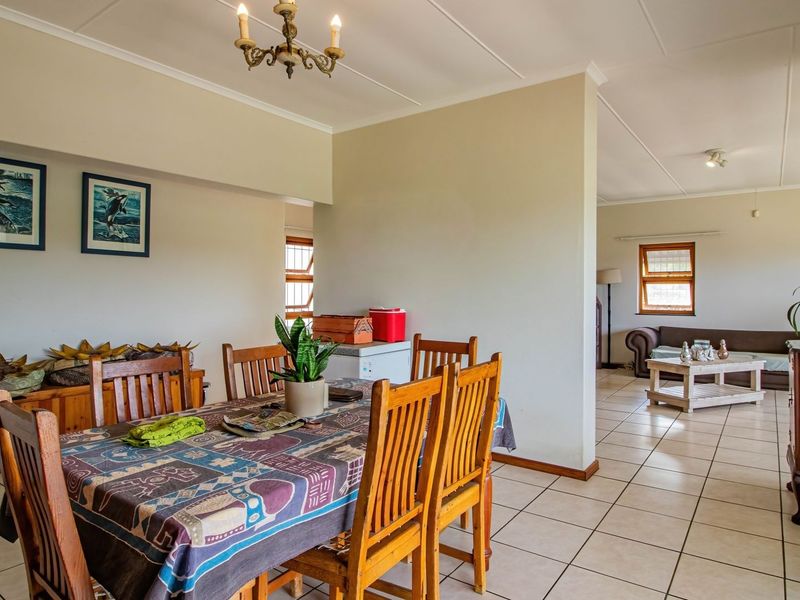Spacious open-plan living and dining area featuring neutral wall tones, tiled flooring, and large windows allowing for natural light.