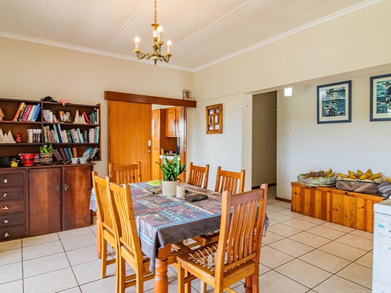 A dining room featuring tiled flooring, a coved ceiling, and a built-in wooden shelving unit, with a sliding door leading to the kitchen area.